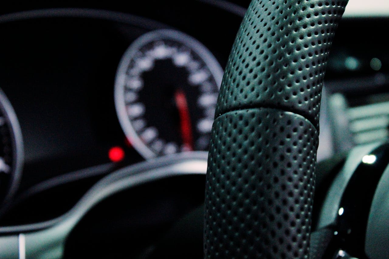 Close-up view of a car's modern steering wheel and dashboard with focus on design and technology.